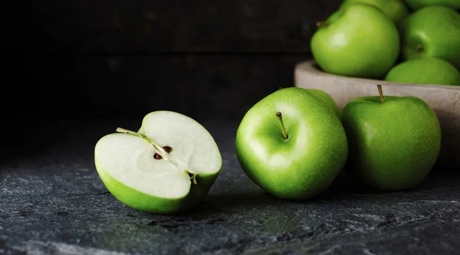whole and half granny smith apples to show what the variety looks like