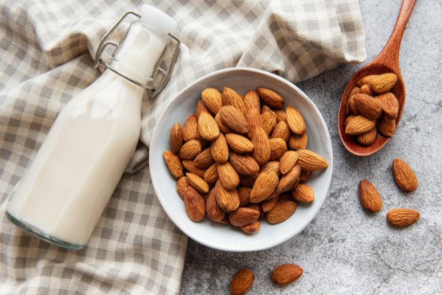 Table with a bowl of almonds and a bottle of almond milk