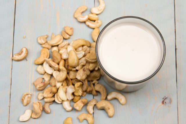 Table of cashews and a cup of cashew milk