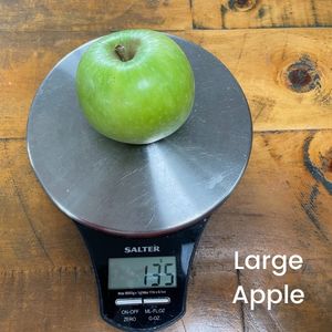 image to show a large apple on a scale weighs 135g