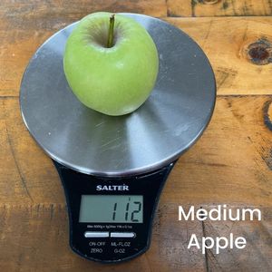 image to show a medium apple on a scale weighing 112g