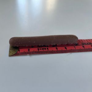 Cadbury chocolate finger on a tape measure to show its length is just over 3 inches