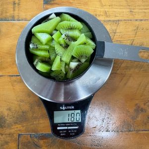 image to show a US cup of kiwi fruit on a scale weighs 180g