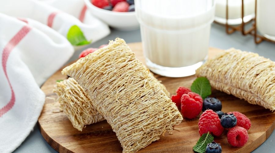 showing two shredded wheats with an example of berry and milk toppings