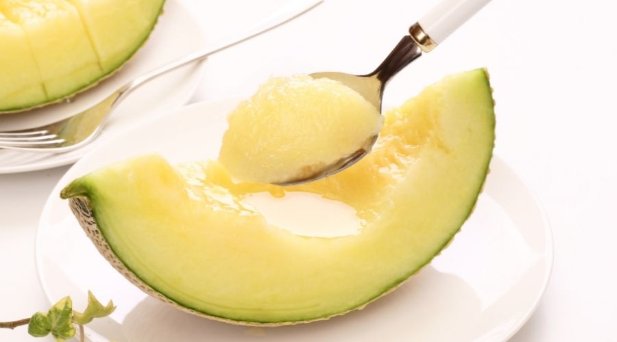 wedge serving of cantaloupe melon being eaten with a spoon